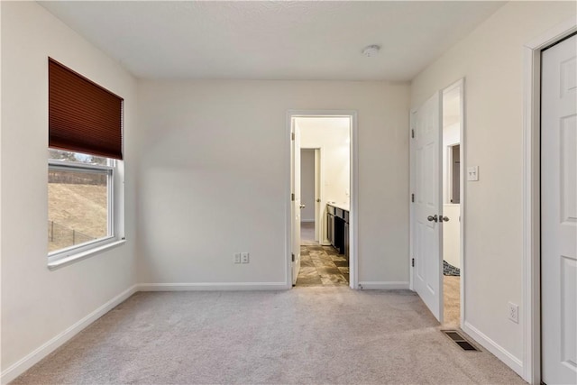 unfurnished bedroom with carpet floors, baseboards, visible vents, and ensuite bathroom