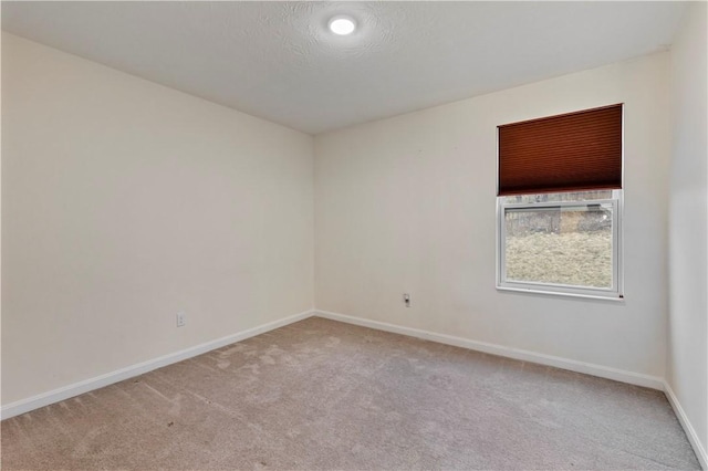 unfurnished room with light carpet, baseboards, and a textured ceiling