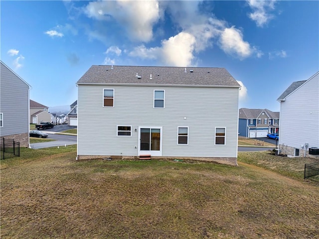 back of property featuring a lawn and fence