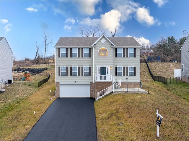 view of front of house featuring an attached garage, fence, aphalt driveway, and a front yard