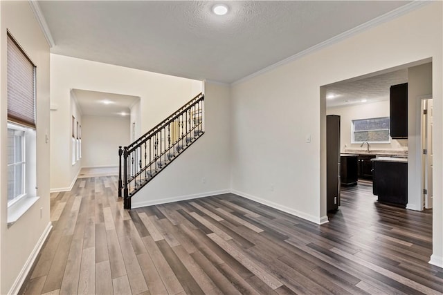 interior space with crown molding, dark wood-type flooring, a textured ceiling, baseboards, and stairs