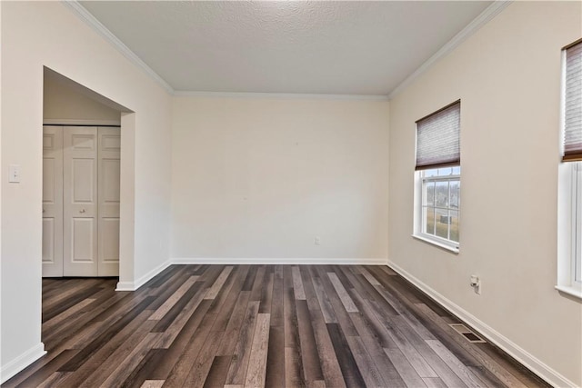 unfurnished bedroom with ornamental molding, dark wood-type flooring, a textured ceiling, and baseboards