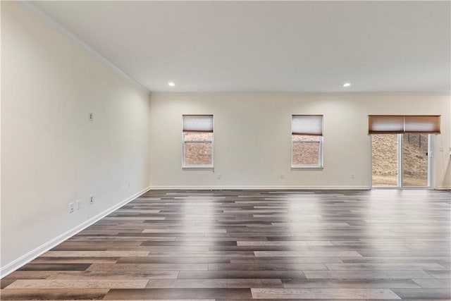 empty room featuring crown molding, dark wood-style flooring, recessed lighting, and baseboards