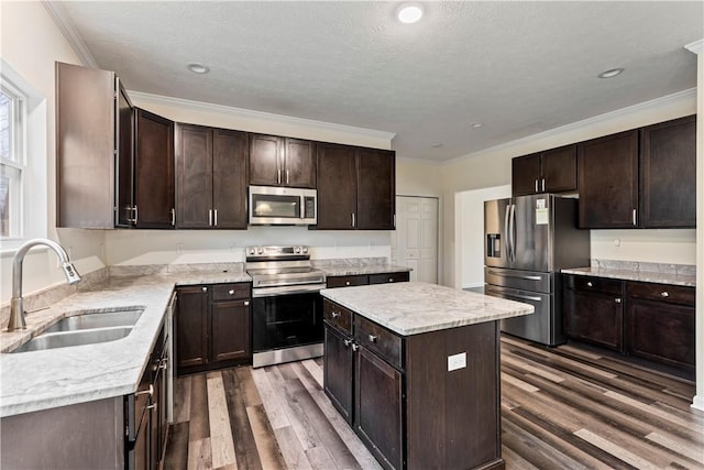 kitchen featuring stainless steel appliances, a sink, dark brown cabinetry, and wood finished floors