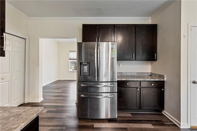 kitchen with dark brown cabinets, ornamental molding, dark wood-style flooring, and stainless steel fridge