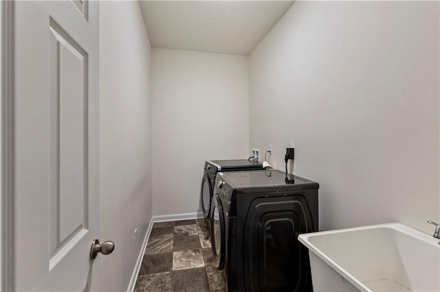 laundry room featuring washing machine and dryer, stone finish floor, a sink, laundry area, and baseboards