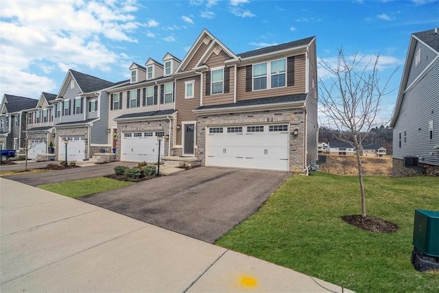 view of front of home featuring an attached garage, stone siding, driveway, a residential view, and a front yard