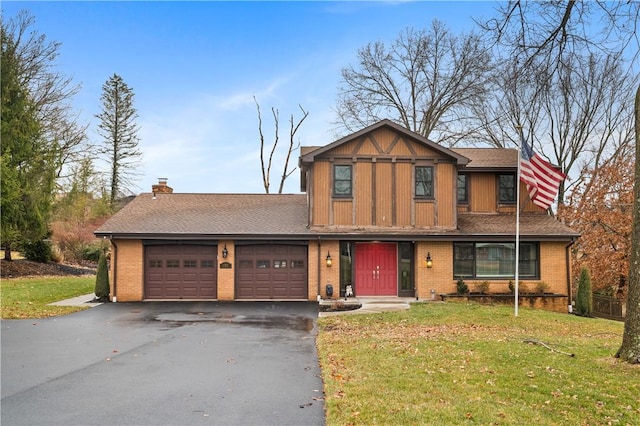 view of front of house featuring a garage, aphalt driveway, a front yard, and brick siding