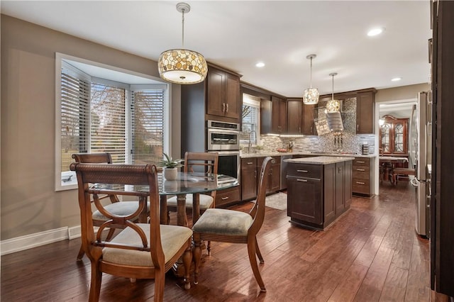 kitchen with a center island, dark wood-style flooring, tasteful backsplash, double oven, and dark brown cabinets