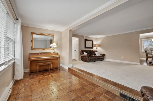 living area featuring baseboards, visible vents, and crown molding