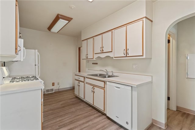 kitchen with white appliances, a sink, visible vents, light countertops, and light wood-type flooring