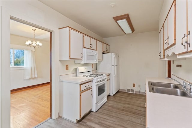 kitchen with light wood-style floors, white appliances, visible vents, and a sink