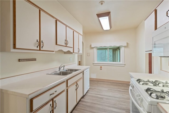 kitchen featuring white appliances, a sink, baseboards, light wood-style floors, and light countertops