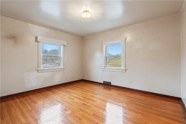 spare room featuring visible vents, light wood finished floors, a wealth of natural light, and baseboards