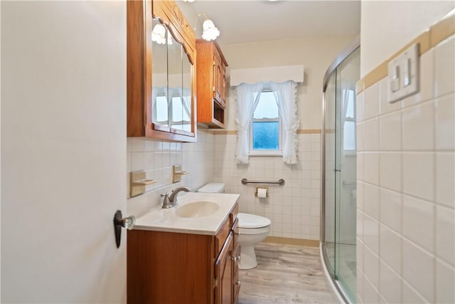 full bath featuring toilet, wood finished floors, vanity, tile walls, and a stall shower