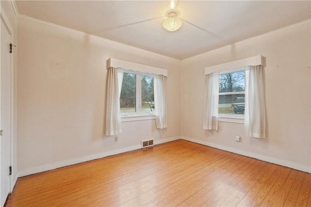 unfurnished room featuring ornamental molding, wood finished floors, visible vents, and baseboards