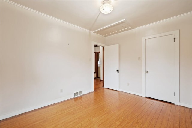 interior space featuring attic access, baseboards, visible vents, and light wood finished floors