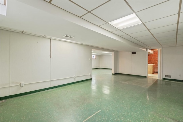 finished below grade area with a paneled ceiling, visible vents, and baseboards