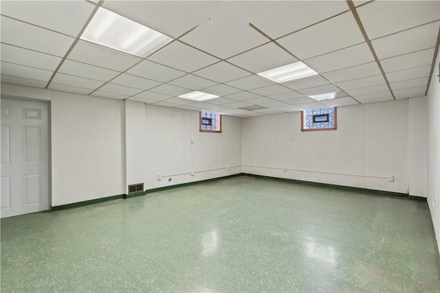 basement featuring baseboards, visible vents, and a drop ceiling