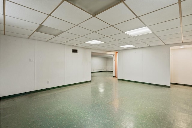 finished basement featuring a drop ceiling, visible vents, and baseboards