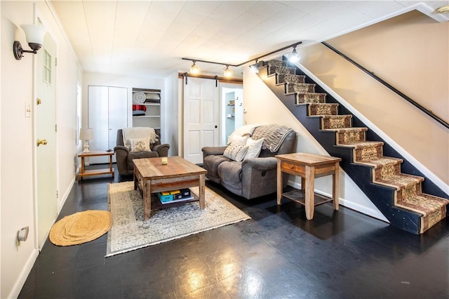 living room featuring rail lighting, a barn door, stairway, and baseboards