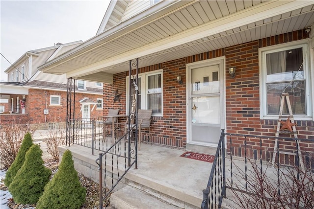 property entrance with a porch and brick siding