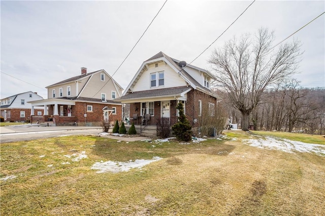 view of front of house with covered porch, brick siding, and a front lawn