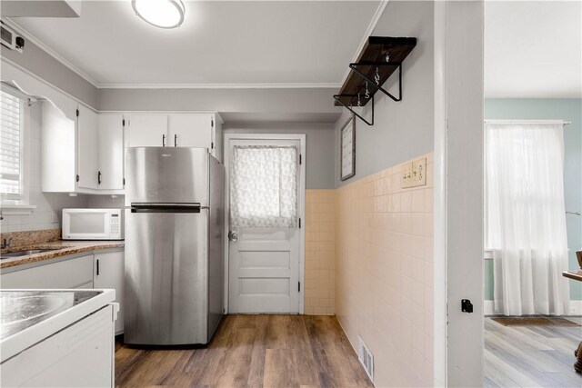 kitchen featuring freestanding refrigerator, wood finished floors, white cabinets, and white microwave