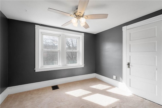 unfurnished room with carpet flooring, ceiling fan, visible vents, and baseboards