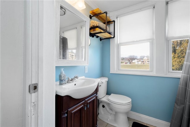 bathroom with toilet, a shower with shower curtain, vanity, and baseboards