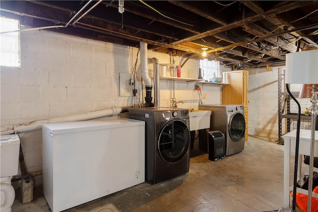 clothes washing area featuring washing machine and dryer, laundry area, and a sink