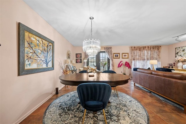 dining area featuring rail lighting, baseboards, a chandelier, and tile patterned flooring