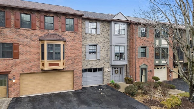 multi unit property featuring brick siding, driveway, and an attached garage