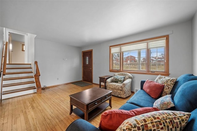 living room featuring stairs, baseboards, and wood finished floors