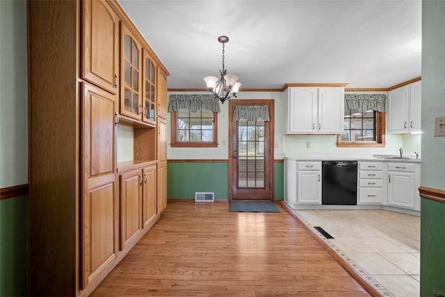 kitchen with black dishwasher, visible vents, glass insert cabinets, hanging light fixtures, and a notable chandelier