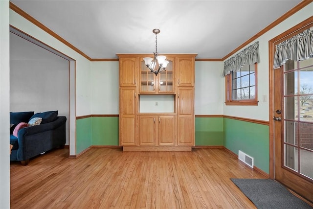 dining room with a notable chandelier, visible vents, baseboards, light wood finished floors, and crown molding