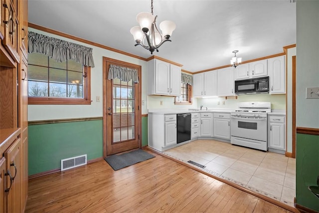 kitchen with visible vents, an inviting chandelier, light wood-style floors, ornamental molding, and black appliances