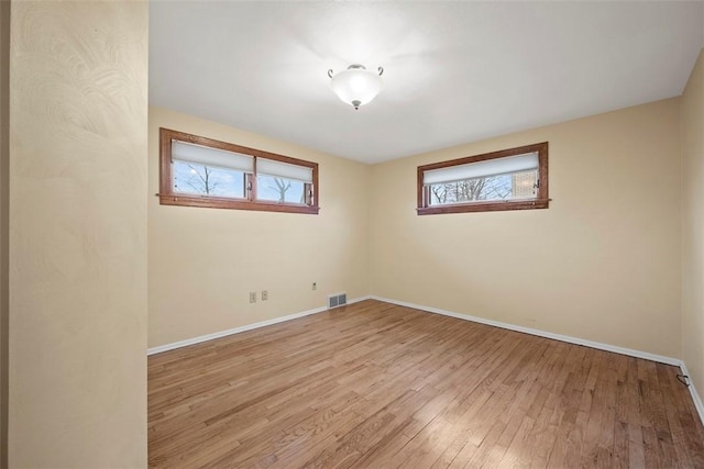 unfurnished room with light wood-style floors, visible vents, and baseboards