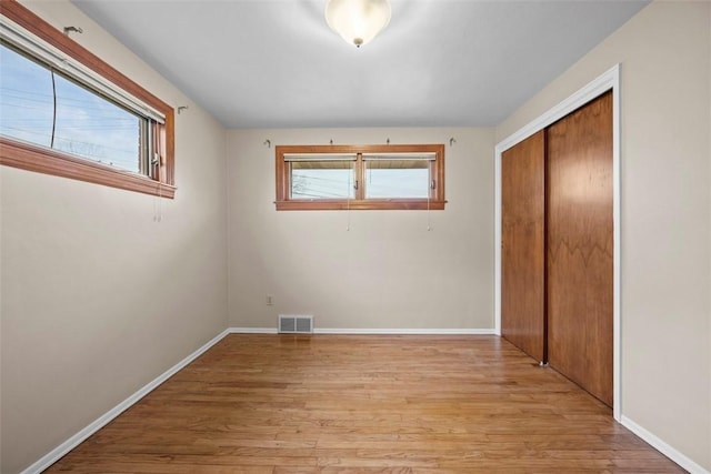 unfurnished bedroom featuring light wood finished floors, a closet, visible vents, and baseboards