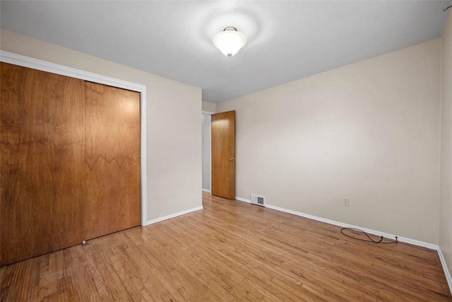 unfurnished bedroom featuring light wood-style floors, baseboards, visible vents, and a closet