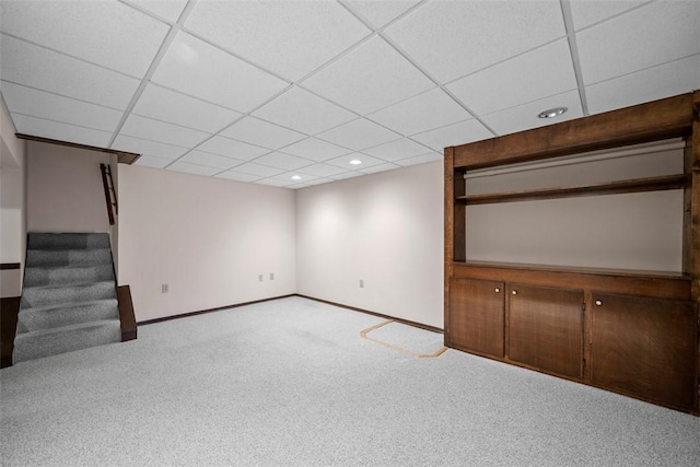 finished below grade area featuring a paneled ceiling, recessed lighting, baseboards, stairway, and carpet