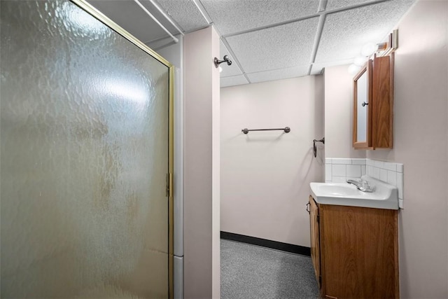 full bath featuring a paneled ceiling, a shower stall, baseboards, and vanity