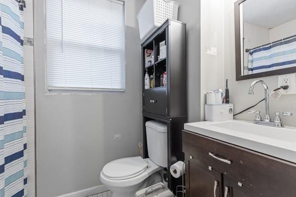 bathroom with a shower with shower curtain, baseboards, vanity, and toilet