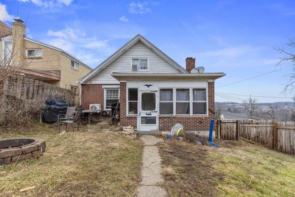 view of front of house featuring an outdoor fire pit, fence, and brick siding