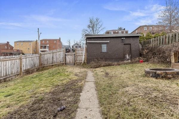 view of yard featuring an outdoor fire pit, a fenced backyard, and an outdoor structure