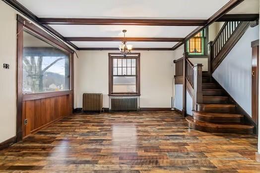 unfurnished room featuring a wealth of natural light, radiator heating unit, and wood finished floors