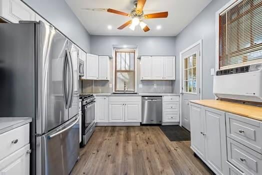 kitchen featuring appliances with stainless steel finishes, white cabinetry, a sink, and wood finished floors