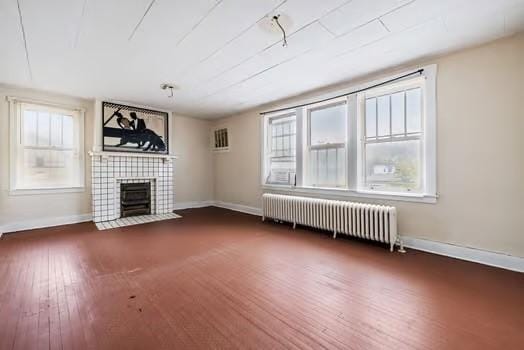 unfurnished living room featuring baseboards, a fireplace, wood finished floors, and radiator