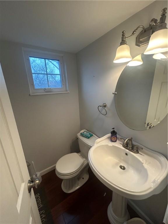 bathroom featuring a sink, wood finished floors, toilet, and baseboards