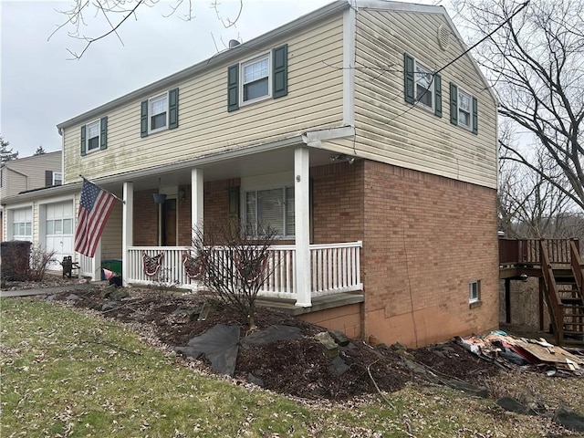 view of front facade featuring a porch, brick siding, and a garage